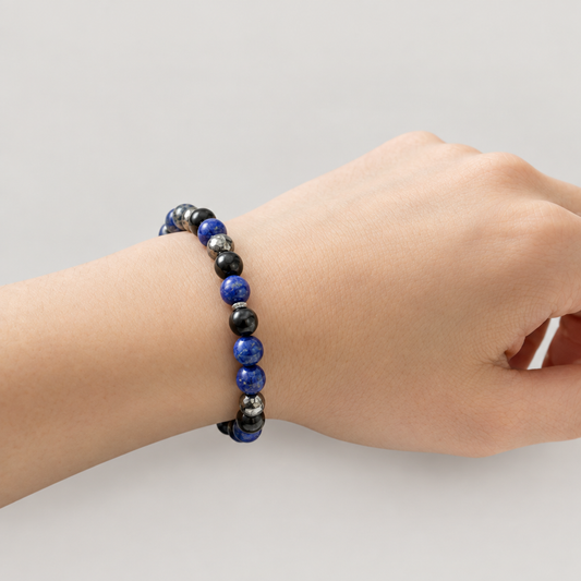Black-and-blue bracelet on the wrist with a light warm-grey background