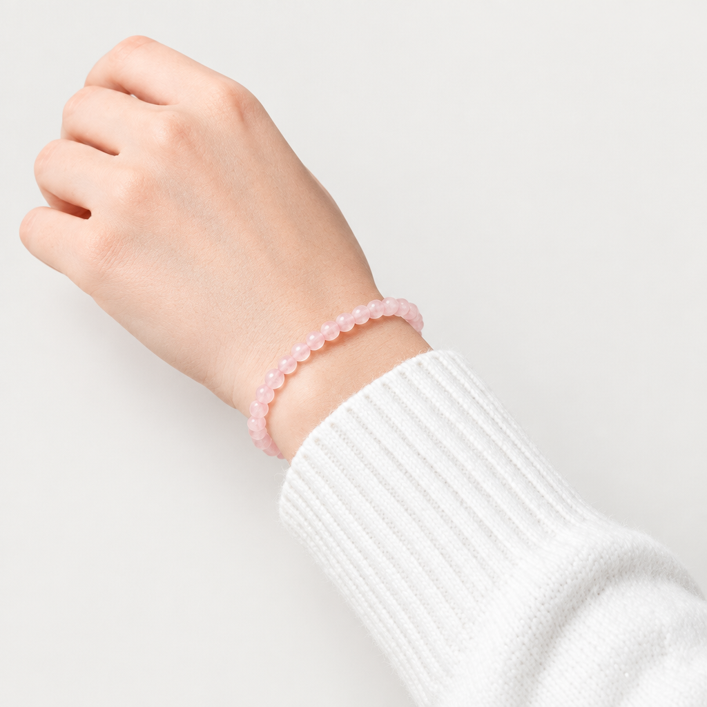 Rose quartz bracelet on wrist with a matching light warm-grey background